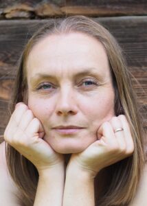 Justyna Szerechan - Orchowska, projektant terenów zieleni. Wizerunek twarzy, patrzy wprost podpierając głowę rękoma.